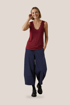 Débardeur Elira en jersey de coton bordeaux avec dentelle fleurie, porté par Mali avec un pantalon marine - Les Stocks du Marais, vue en pied