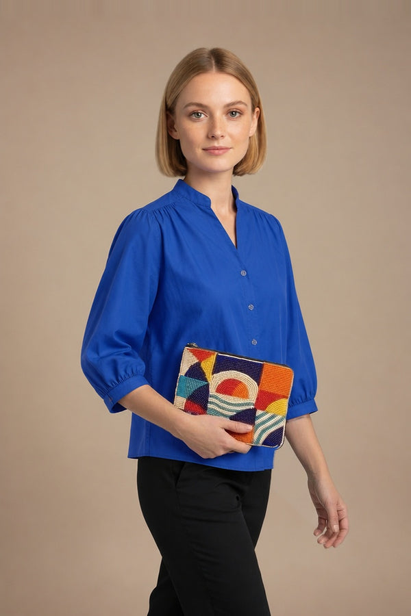 Pochette Jaydi orange perlée portée par la mannequin en chemise Dina bleu roi