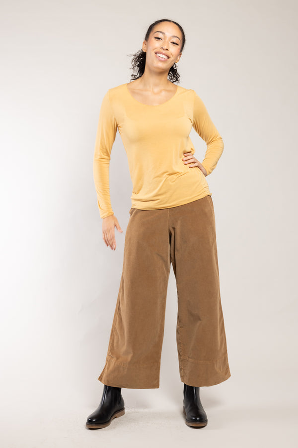 Pantalon Ido velours côtelé ambre Elemente Clemente porté avec un top jaune, silhouette complète