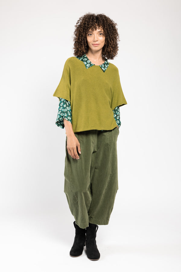 Pull Beli col V vert La Sélection Stocks du Marais, porté sur une chemise imprimée et un pantalon large, silhouette en pied