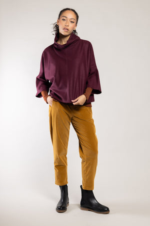 Top Dari laine écoresponsable grenat Elemente Clemente porté avec le pantalon Geishan doré, silhouette complète