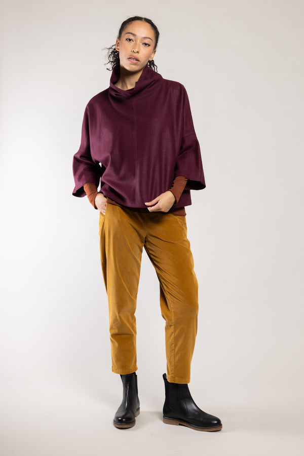 Top Dari laine écoresponsable grenat Elemente Clemente porté avec le pantalon Geishan doré, silhouette complète