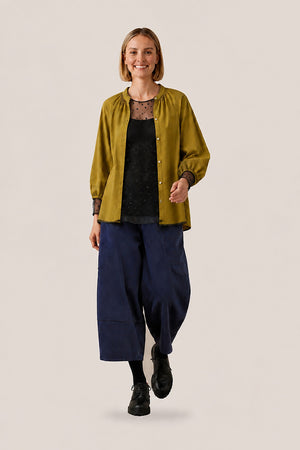 Top transparent à pois floqués noir porté sous une chemise Arta unie ouverte, sorti du pantalon
