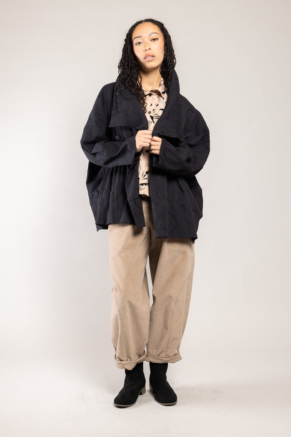 Veste Noby plissé dots noire a.osher portée sur un pantalon beige, silhouette complète