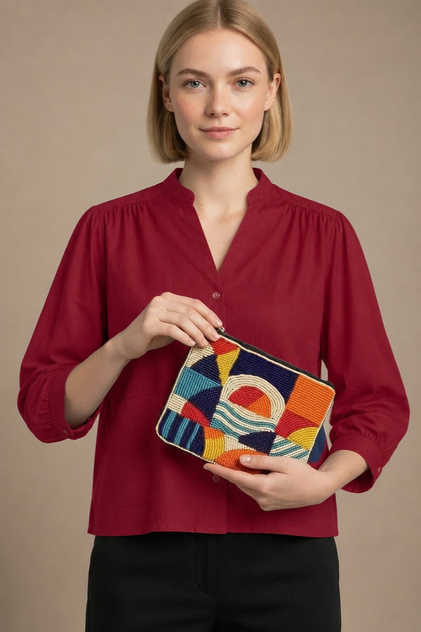 Porte-monnaie Yassy orange perlé porté par la mannequin en chemise Dina rouge